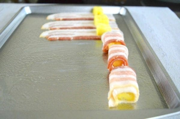 Pineapple being rolled in the bacon