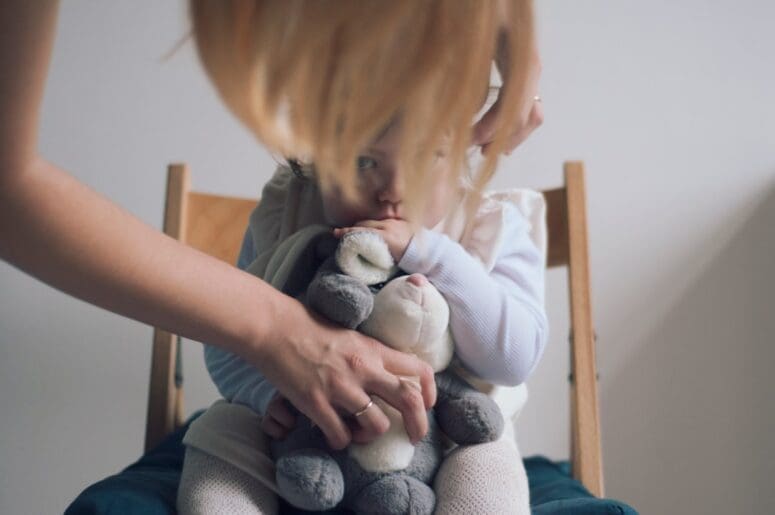 toddler happily holding a well-loved stuffed animal - baby comfort products