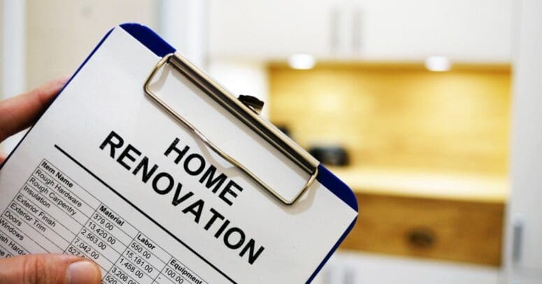 A close-up of a white document on a clipboard with "HOME RENOVATION" as a title and a table of expenses below.